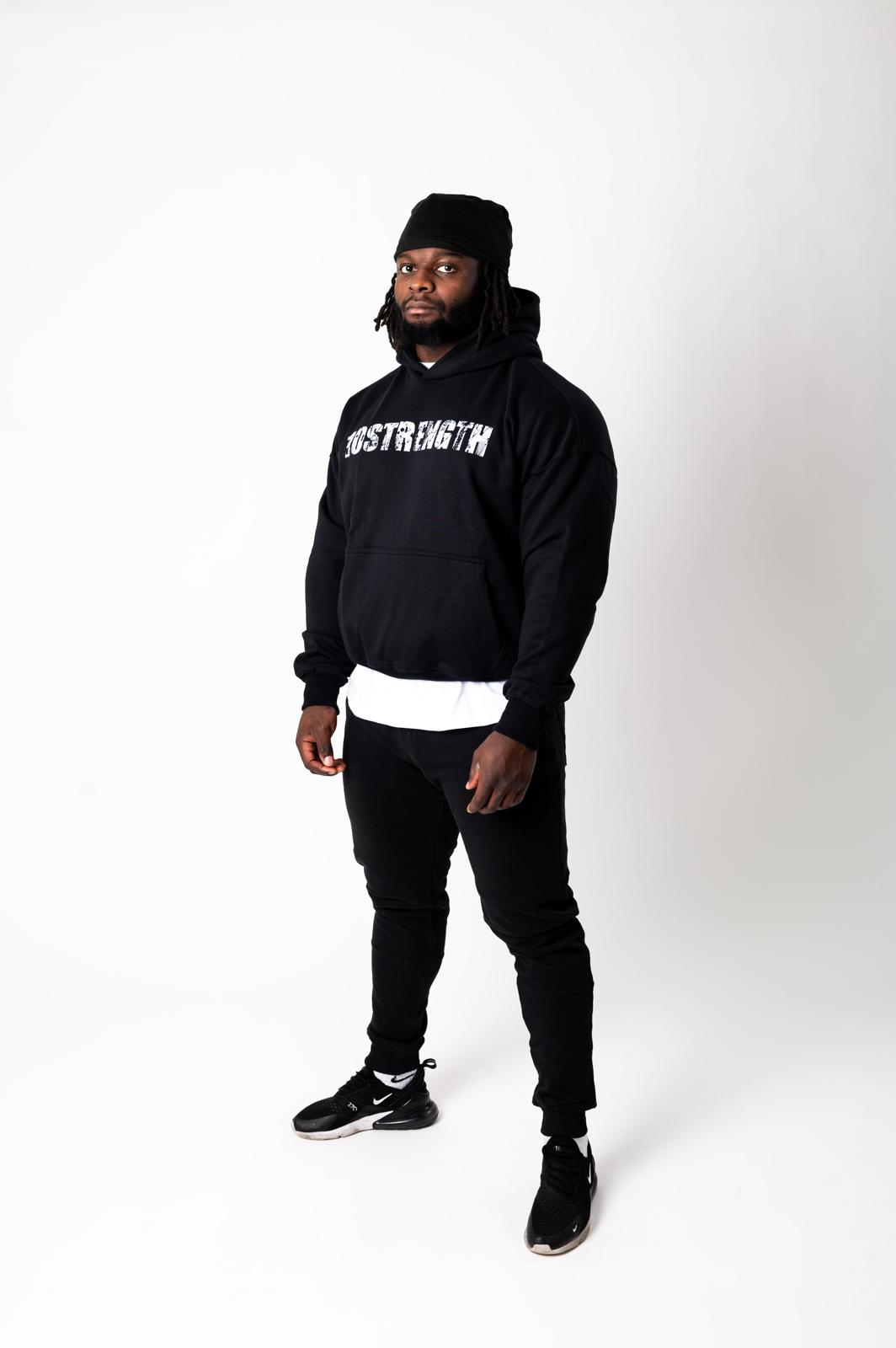 Person wearing a black hoodie with text, black pants, and black shoes on a white background