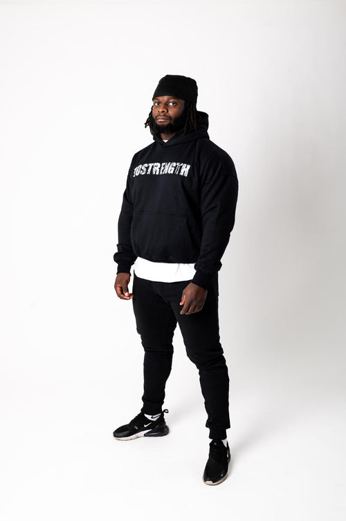 Person wearing a black hoodie with text, black pants, and black shoes on a white background