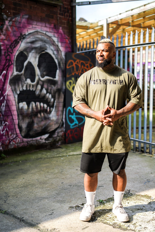 Man standing in front of a graffiti-covered wall with a skull design.